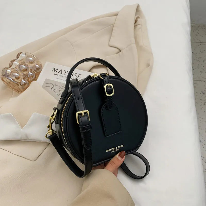sac bandoulière rond cuir noir avec détail doré