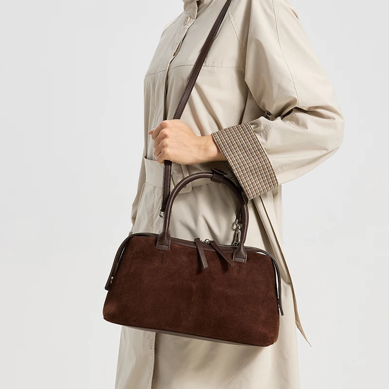 Sac en daim marron foncé porté à l’épaule avec sa sangle amovible