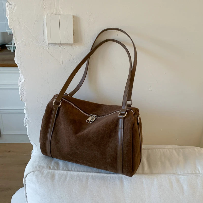 Sac polochon femme marron effet daim posé sur un fauteuil