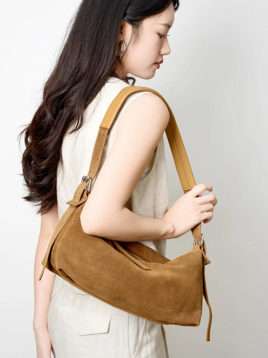 Femme portant le sac en daim caramel à l’épaule avec un gilet en lin