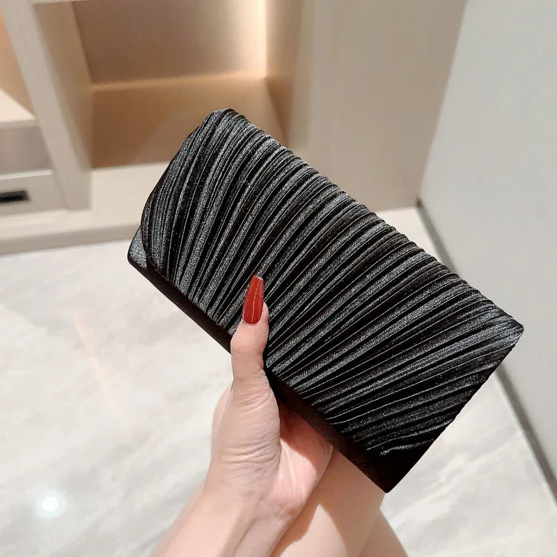 Pochette de soirée noire en satin plissé tenue à la main