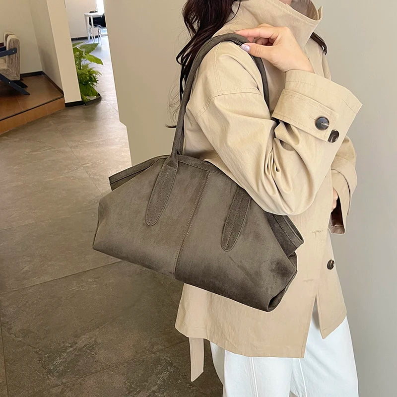 Femme portant le sac suédine kaki à l’épaule avec un trench beige