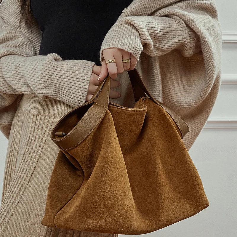 Femme tenant le grand sac en daim cognac à la main