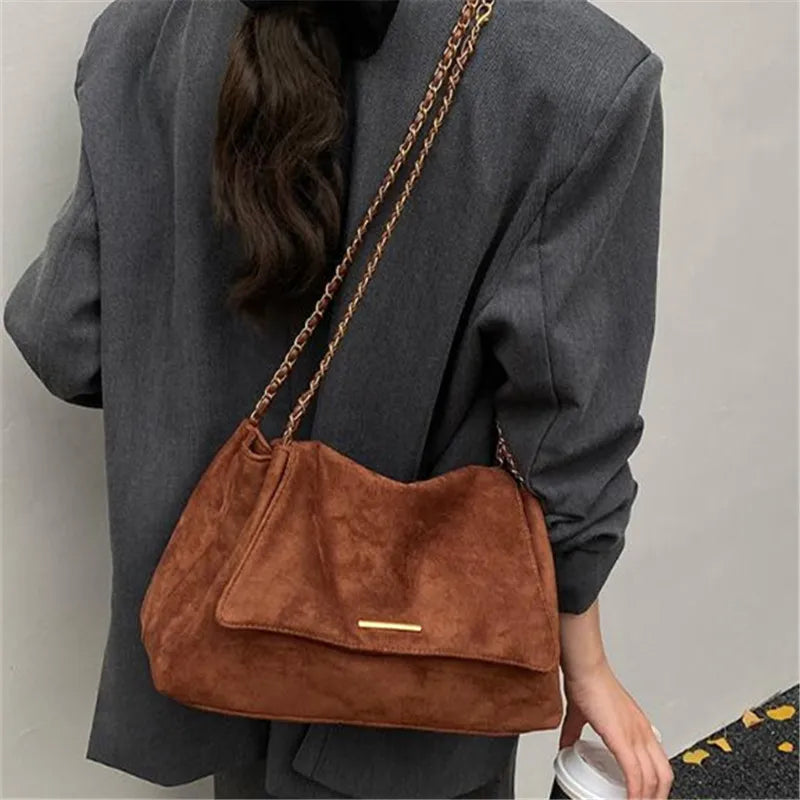 Sac en suédine cognac porté en bandoulière sur un manteau gris