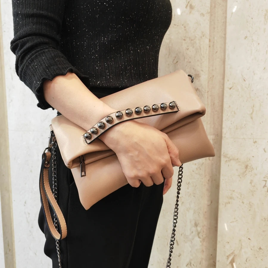Pochette pour femme beige à rivets tenue sous la main