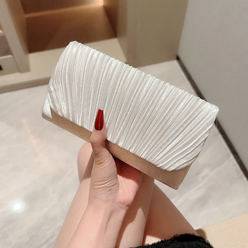 Pochette de soirée blanche en satin plissé tenue à la main