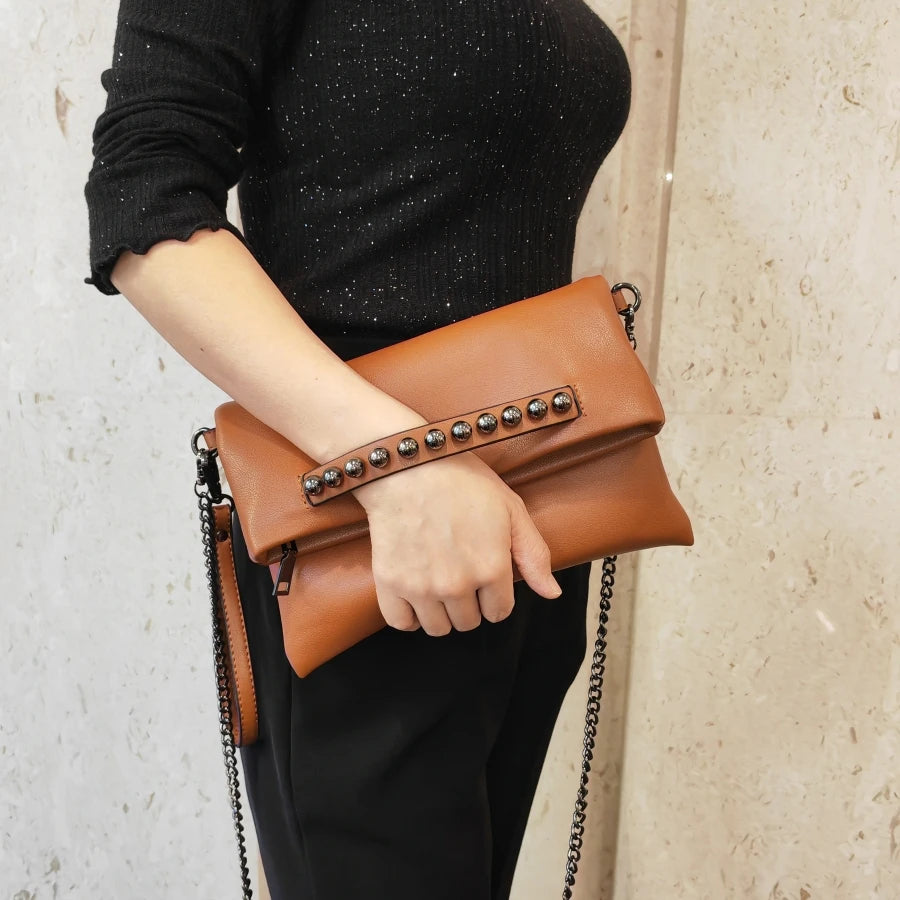 Pochette marron cognac à rivets tenue à la main