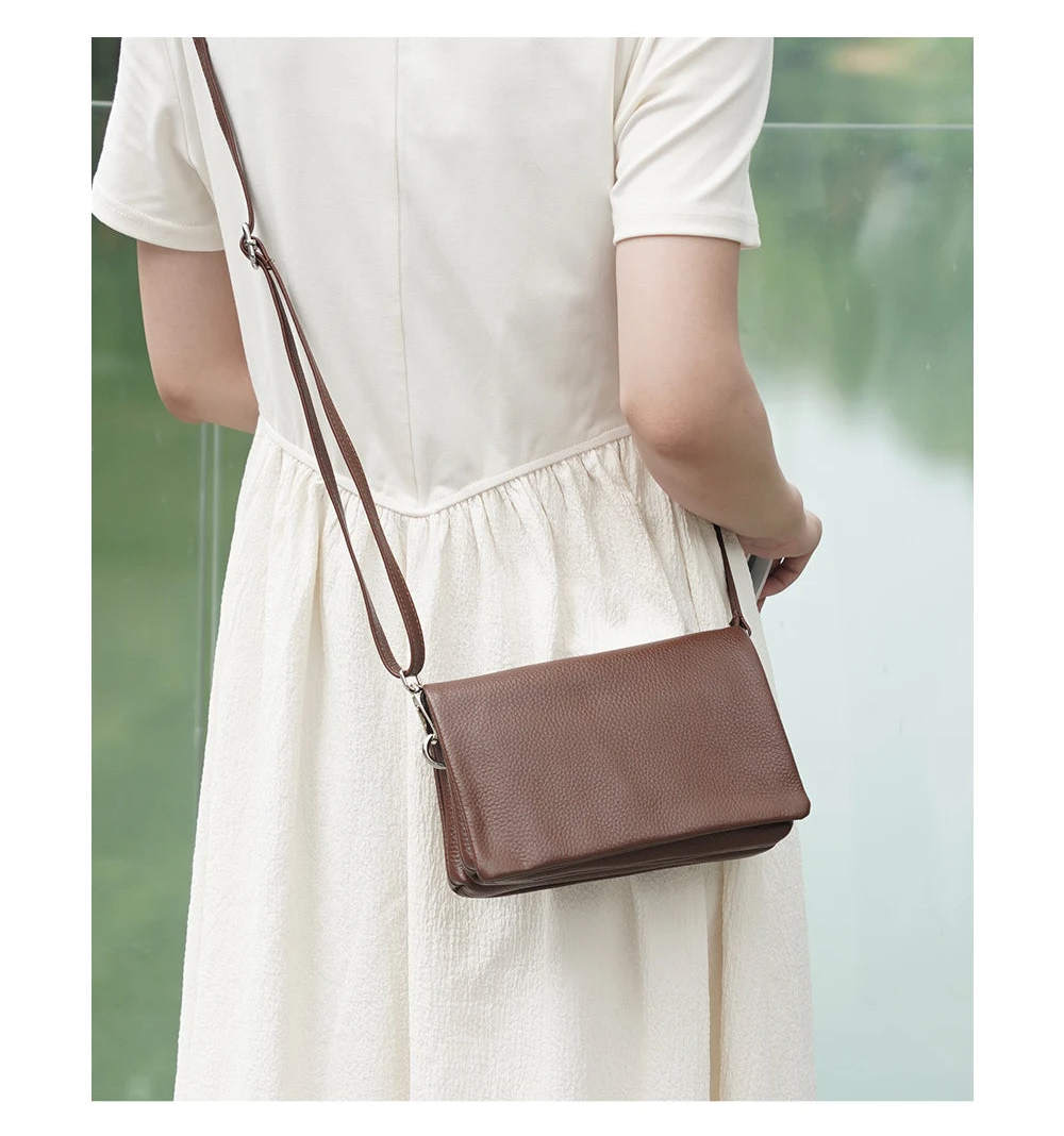 Femme portant la pochette bandoulière en cuir café en travers du corps