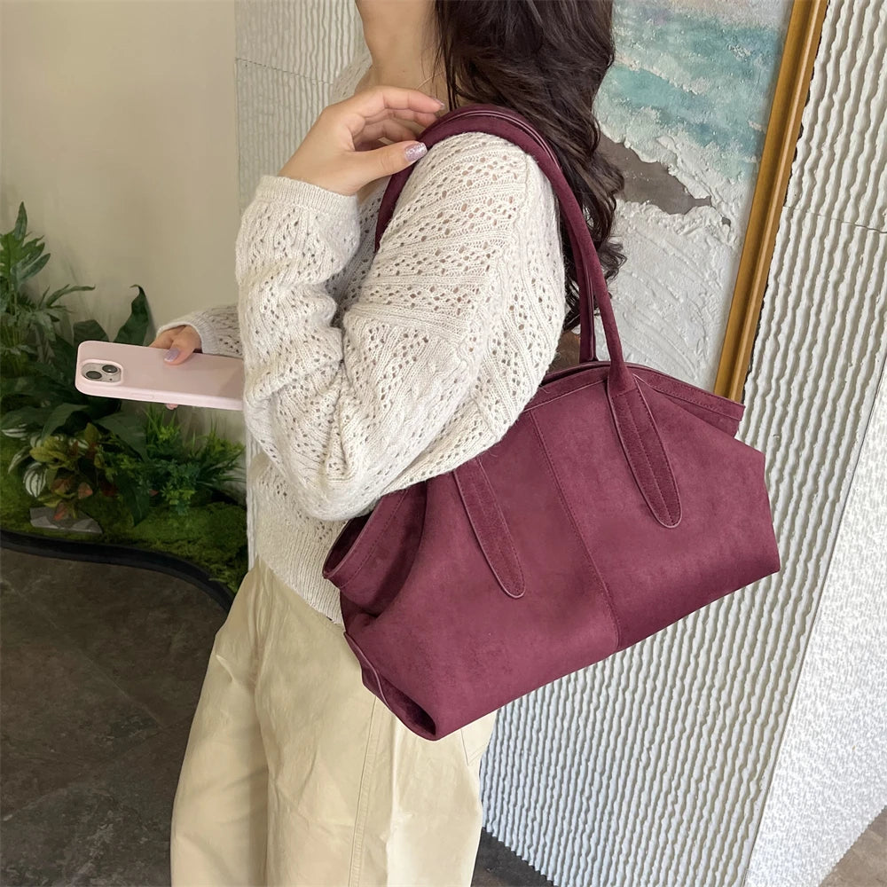 Femme portant le sac suédine bordeaux à l’épaule avec un pull en maille