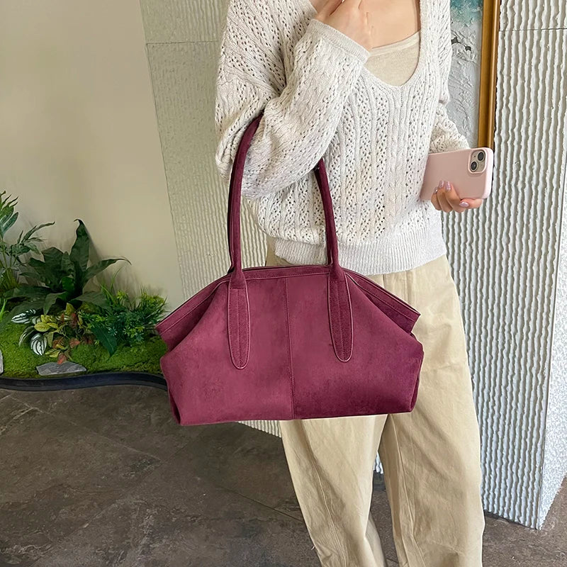 Femme portant le sac suédine bordeaux  avec un pull en maille au bras