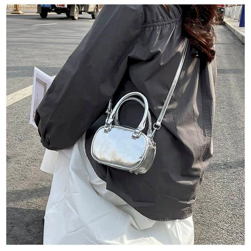 Femme portant le petit sac argenté en bandoulière avec une chemise grise